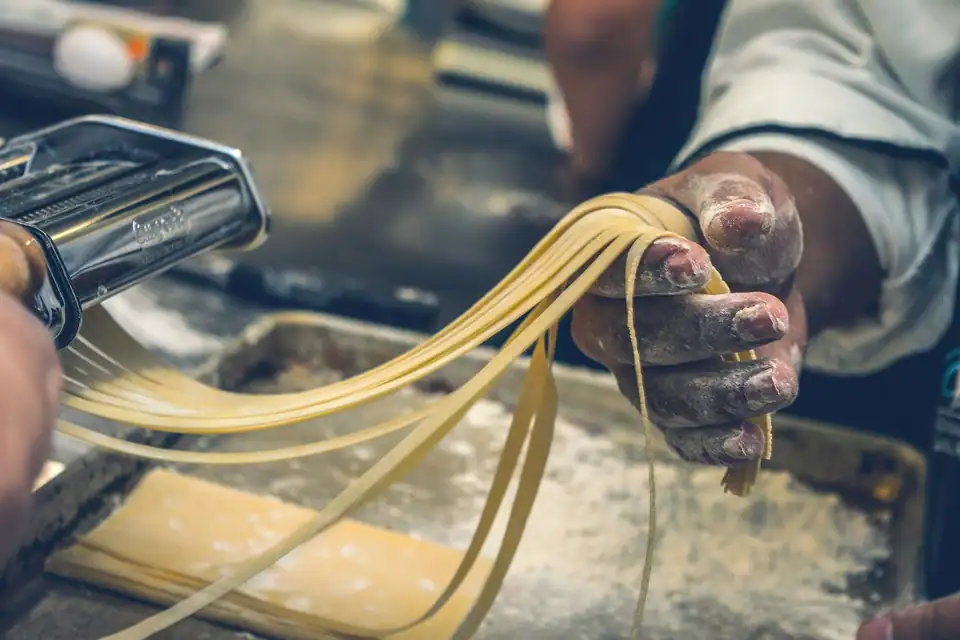 Hands rolling out fresh pasta dough