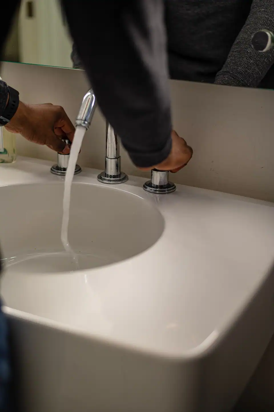 Hands under a running bathroom tap