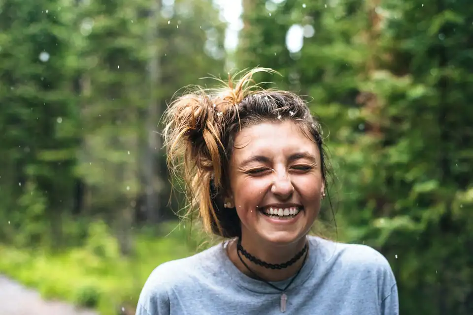 A woman laughing on a forest trail