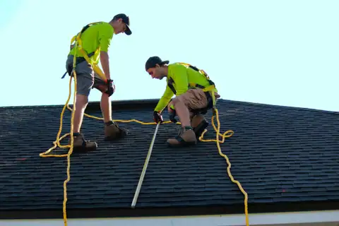Two roofers working on a new shingle roof