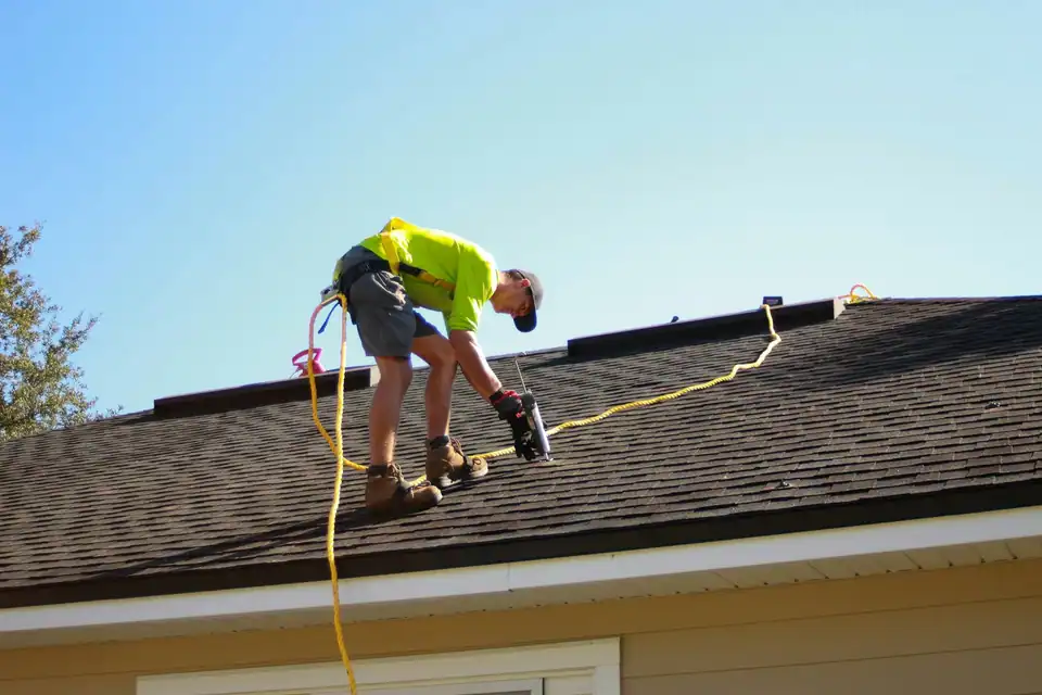 Two roofers working together on a shingle roof
