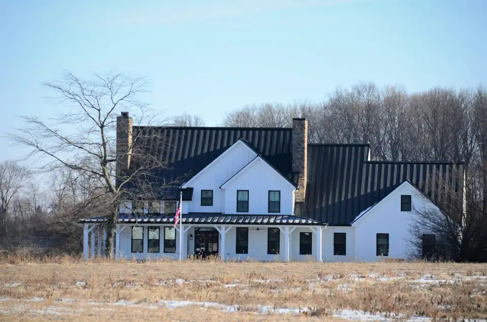 White farmhouse with a black standing-seam metal roof