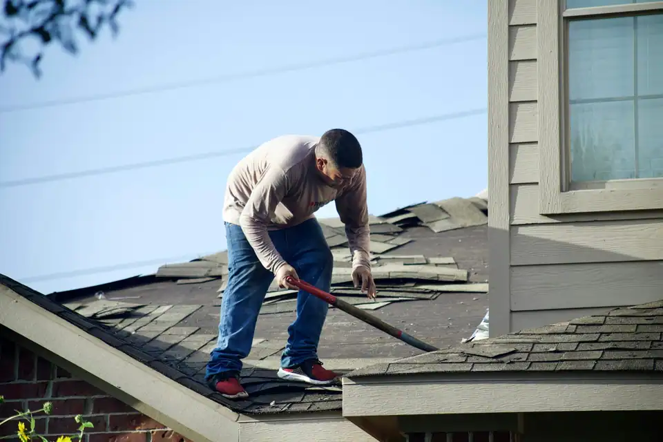 A roofer stripping old shingles off a roof